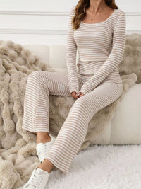 Woman wearing a striped pajama set sitting on a fluffy couch.