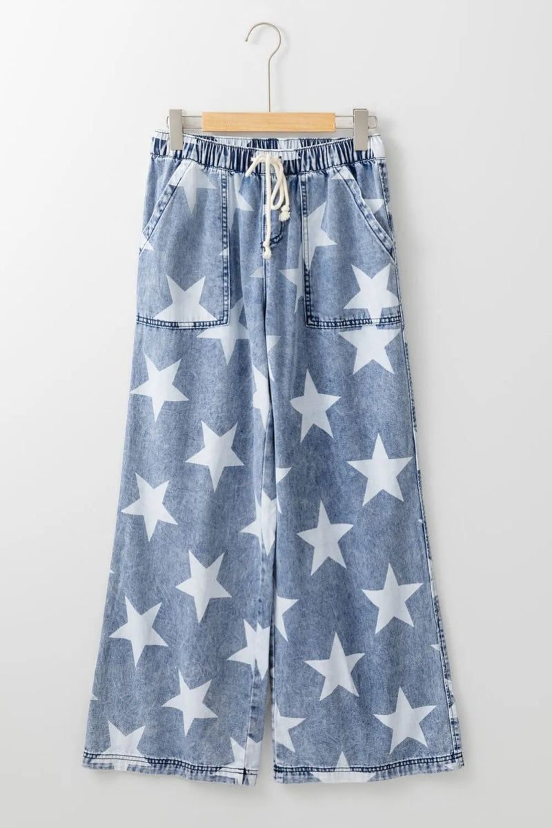 Blue denim pants with white star pattern on a hanger against a white background