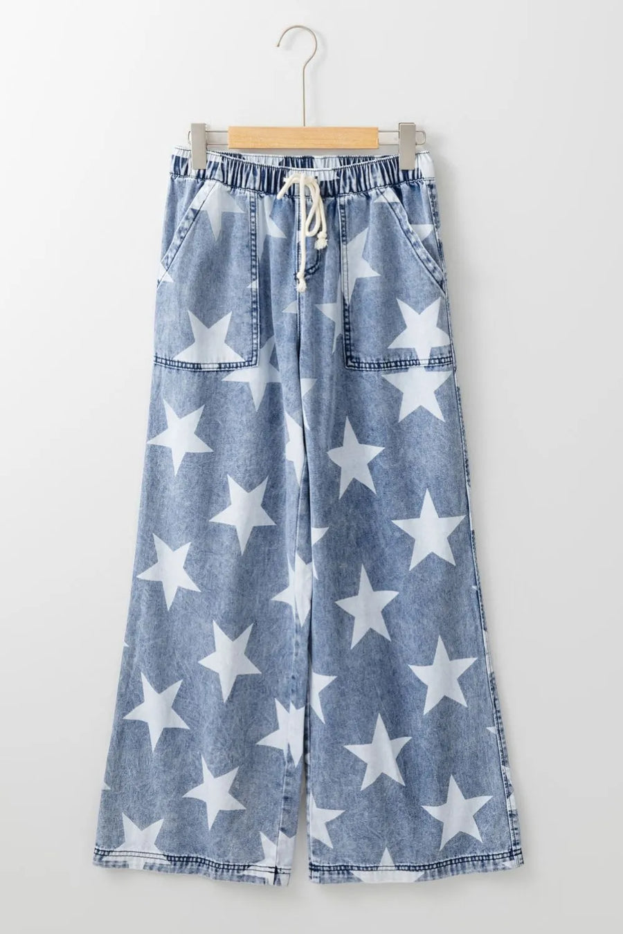 Blue denim pants with white star pattern on a hanger against a white background