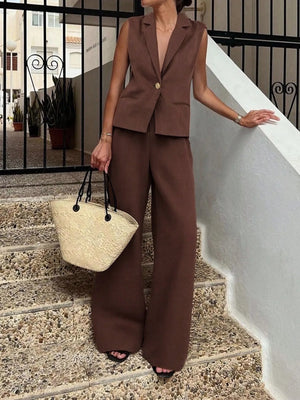 Woman in a brown suit standing on steps with a straw bag.