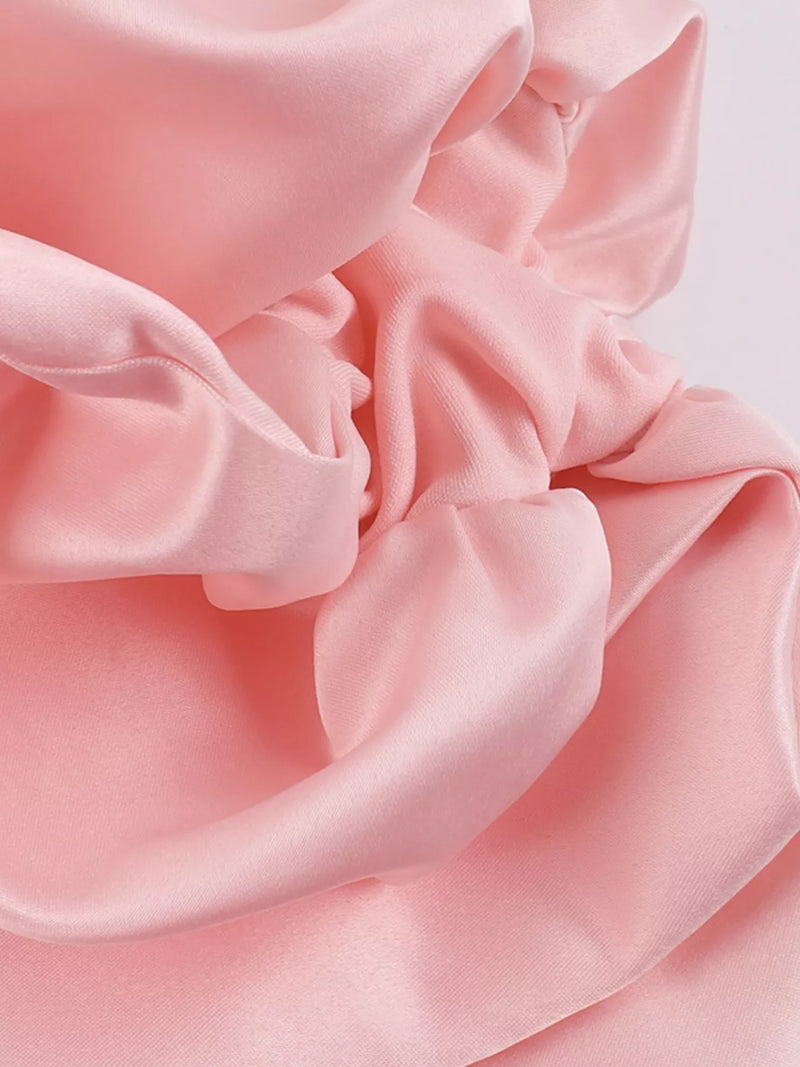 Close-up of pink fabric with soft folds on a light pink background