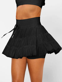 Black ruffled skirt worn by a person on a plain background