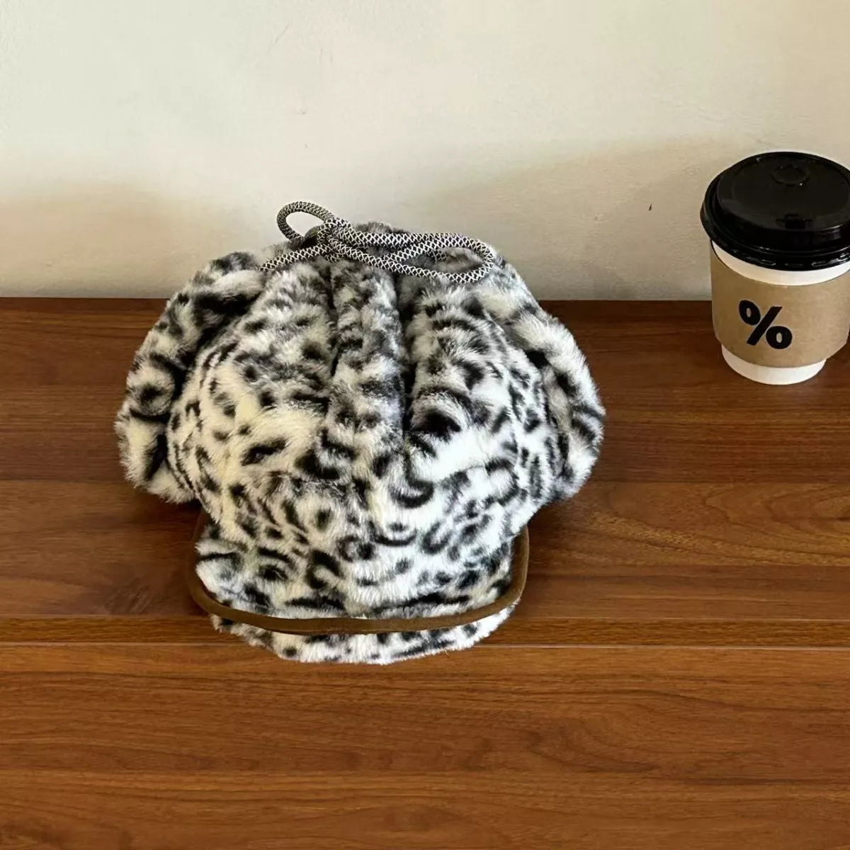 Leopard print bag on a wooden surface with a coffee cup in the background