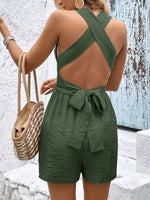 Person wearing a green open-back romper with a textured wall background