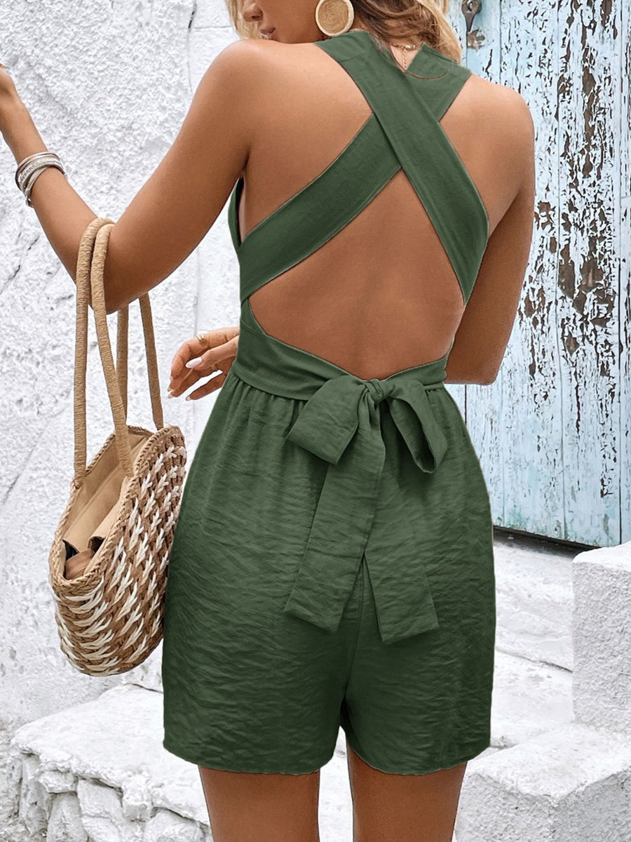 Person wearing a green open-back romper with a textured wall background