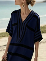 Woman wearing a blue and black patterned dress on a beach.