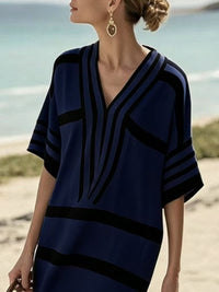 Woman wearing a blue and black patterned dress on a beach.