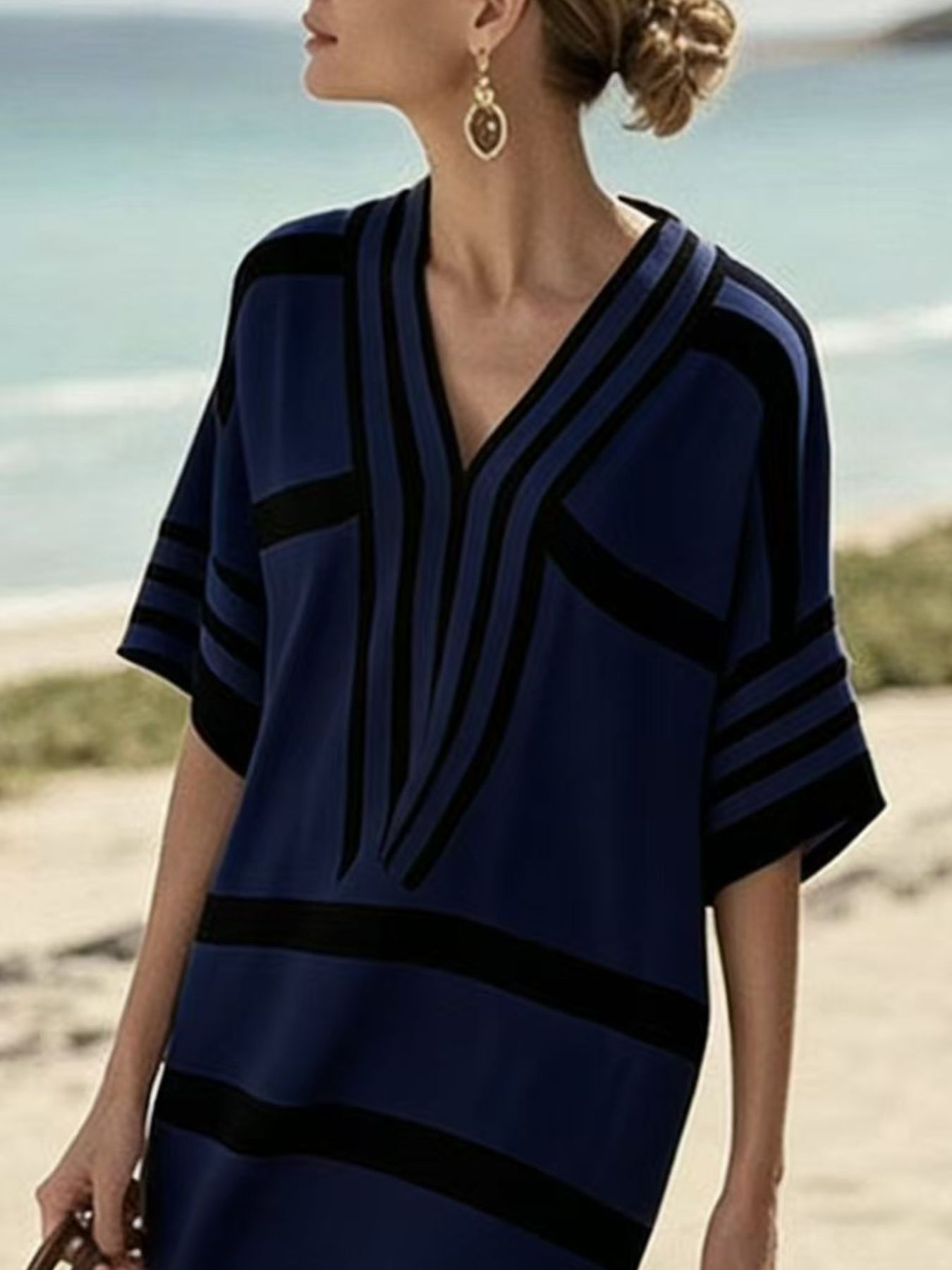 Woman wearing a blue and black patterned dress on a beach.