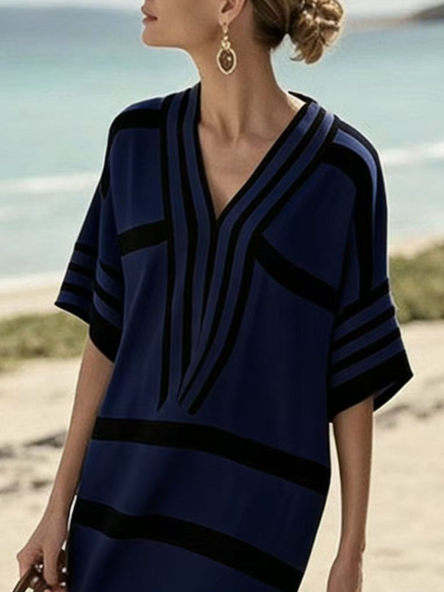 Woman wearing a blue and black patterned dress on a beach.