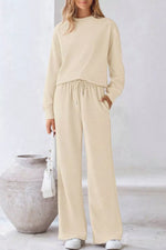 Person wearing a beige outfit standing next to a large pot indoors.