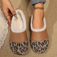 Pair of brown slippers with white fur lining and leopard print soles on a textured surface.