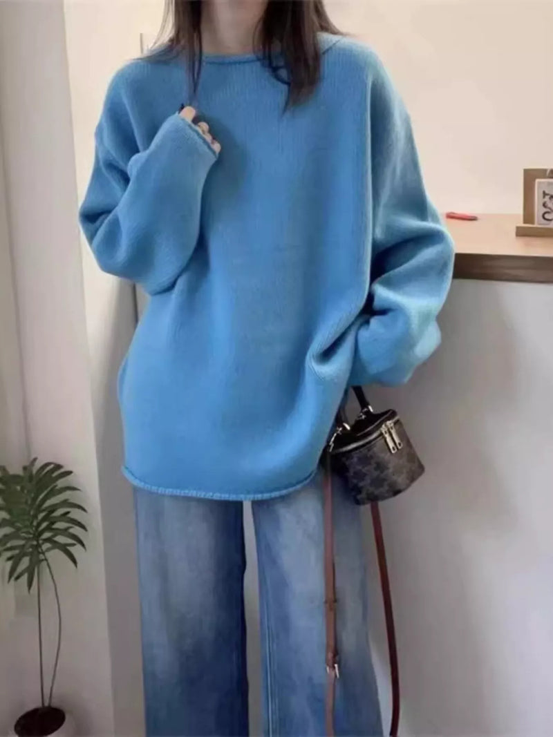 Person wearing a blue sweater and jeans holding a handbag indoors.