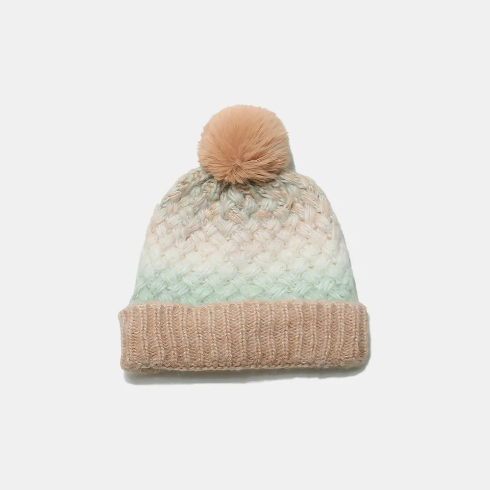 Knitted beanie with a pom-pom on a light gray background