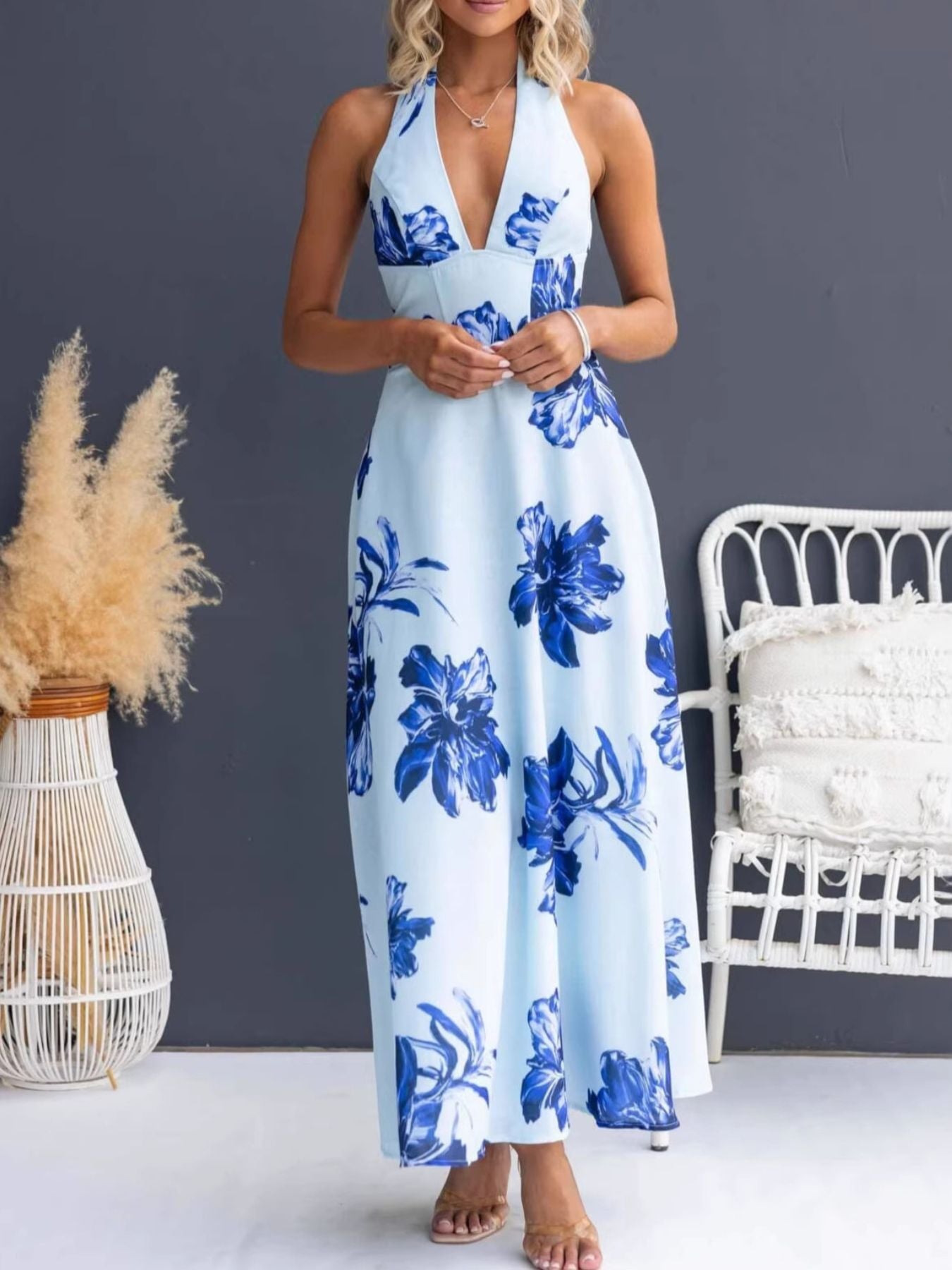 Woman wearing a blue floral dress standing in a room with decorative elements.