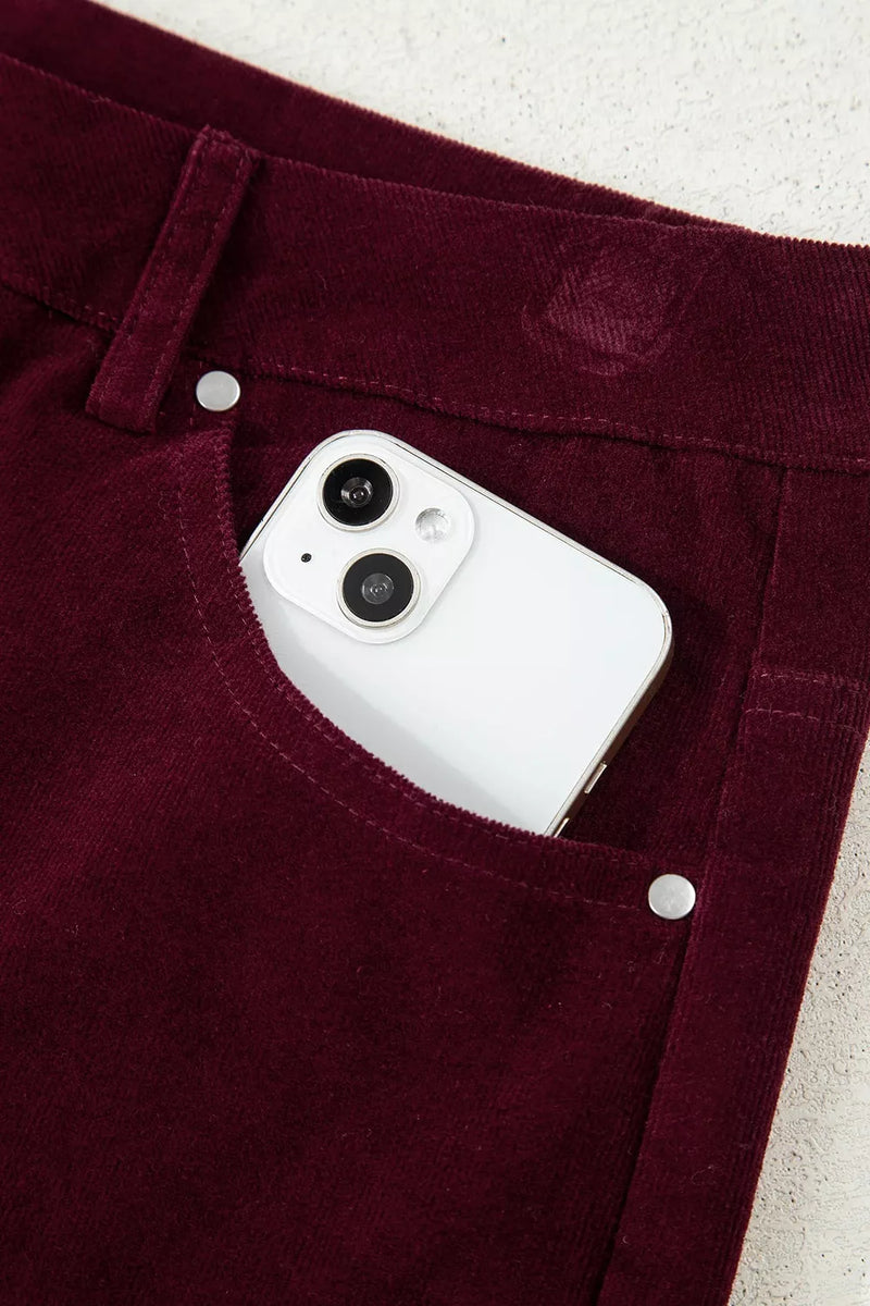 White phone case in a pocket of maroon pants on a light background