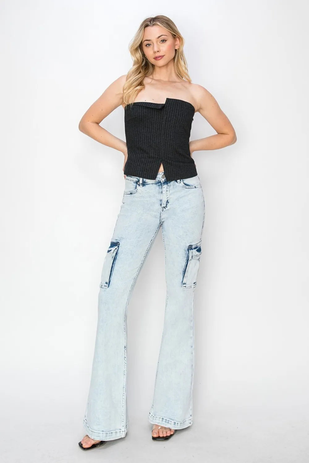 Woman wearing a black strapless top and light blue jeans on a white background