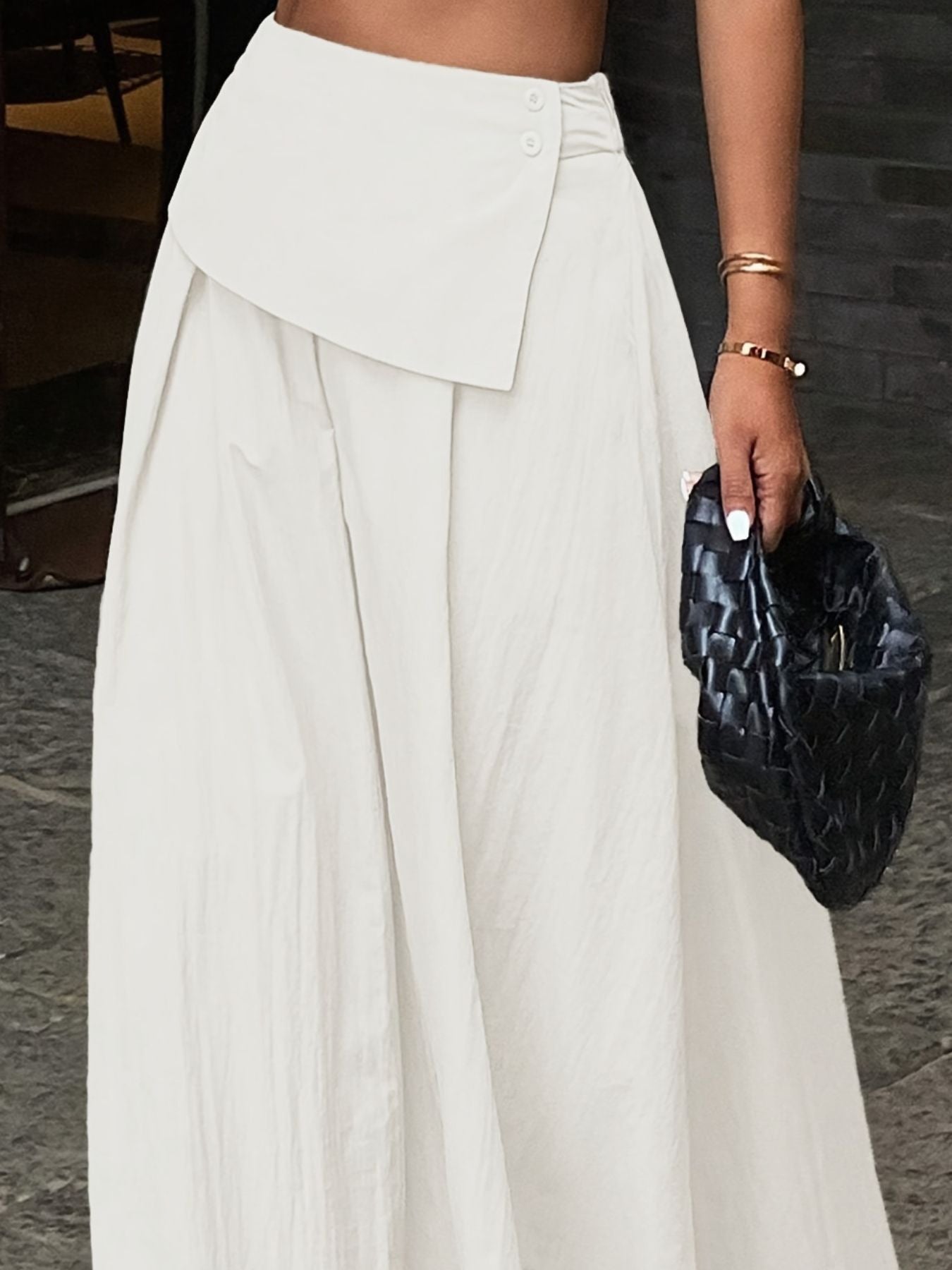 Person wearing a white outfit holding a black clutch.