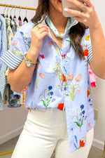 Person wearing a colorful floral scarf with a clothing rack in the background