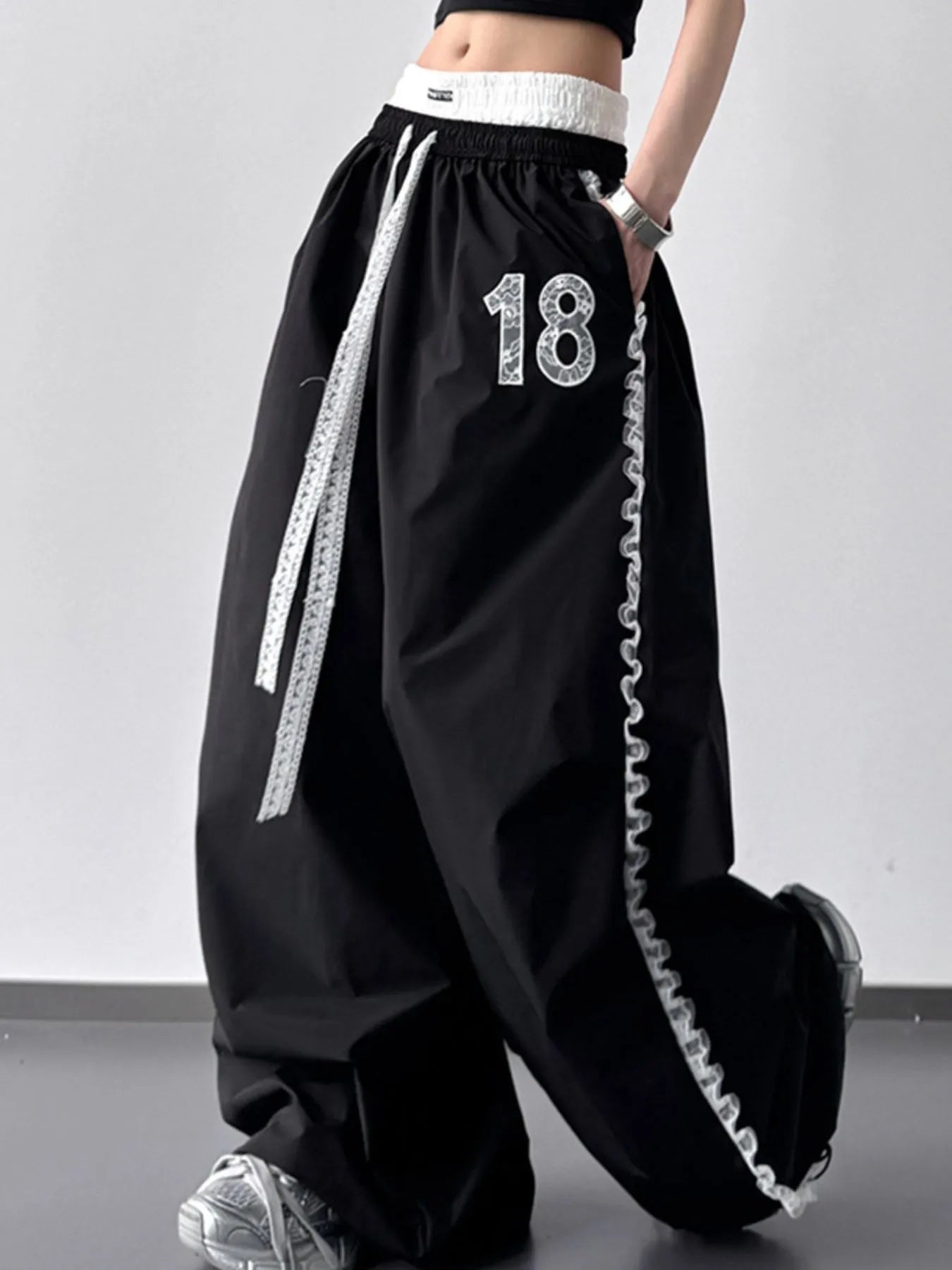 Black wide-leg pants with white drawstring and number '18' on a gray background