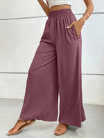 Person wearing mauve wide-leg pants with a white background