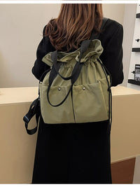 Person wearing a beige drawstring bag over their shoulder with a plain background