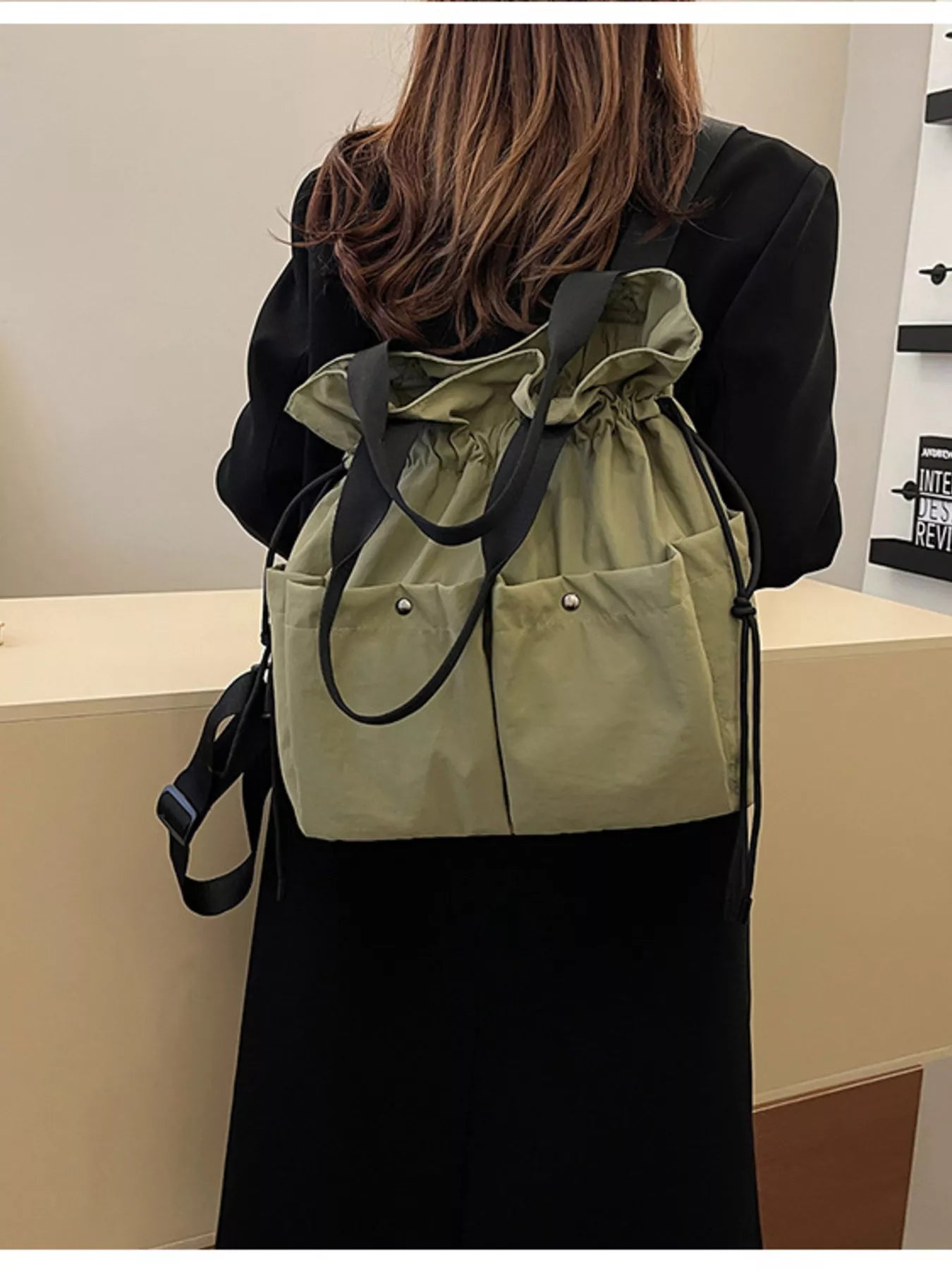 Person wearing a beige drawstring bag over their shoulder with a plain background