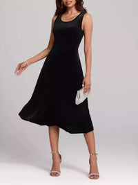 Woman wearing a black sleeveless dress on a plain background