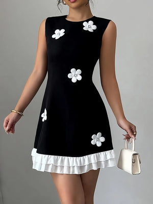 Black dress with white floral patterns worn by a model on a gray background