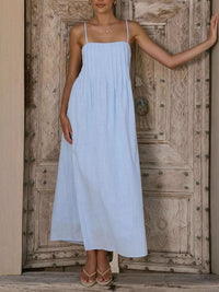 Woman wearing a light blue dress standing in front of a wooden door.