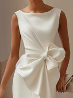 White dress with a large bow detail on a neutral background