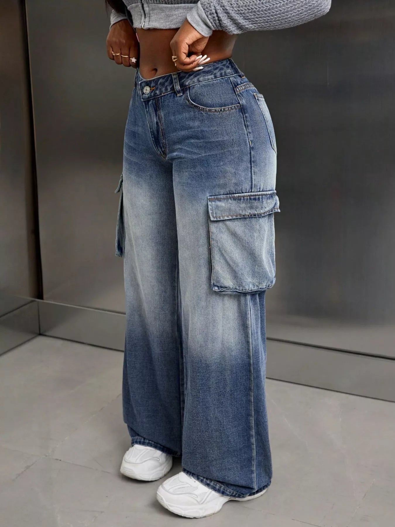Person wearing wide-leg blue jeans with cargo pockets against a neutral background