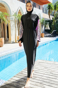Woman in a black swimsuit with a hood standing by a pool.