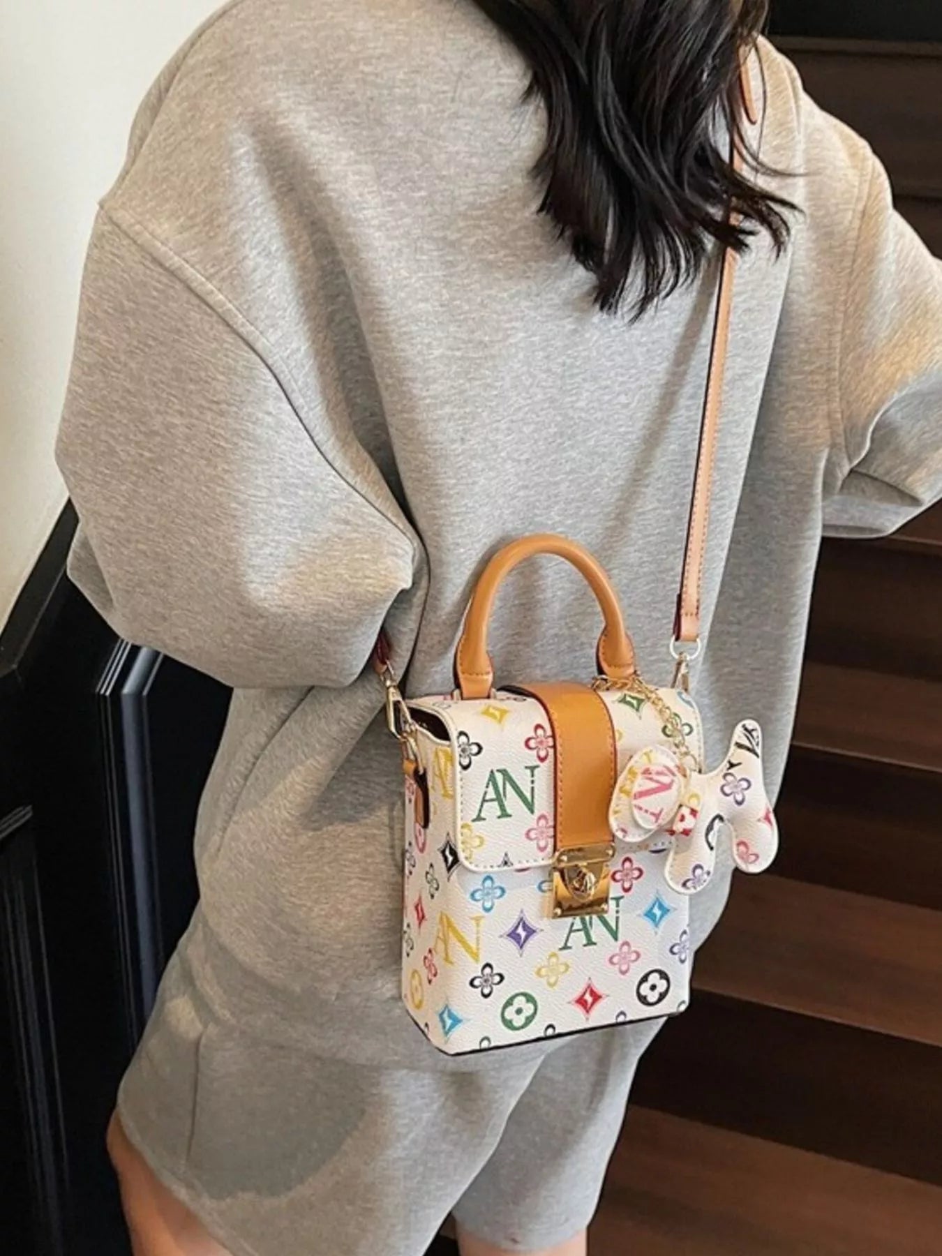 Person wearing a colorful patterned handbag with a visible brand logo.