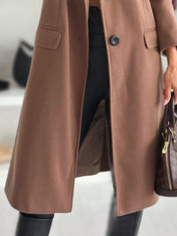 Brown coat worn by a person with a blurred background