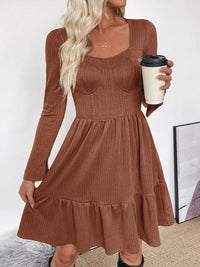 Woman wearing a brown ribbed dress holding a coffee cup on a white background