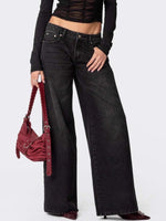 Person wearing black wide-leg jeans and a black top, holding a red handbag on a white background