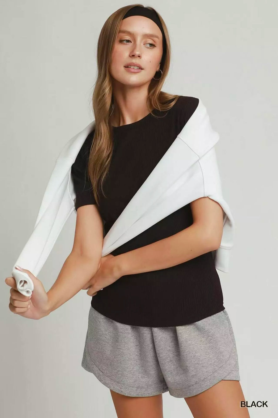 Woman wearing a black and white top with gray shorts on a plain background