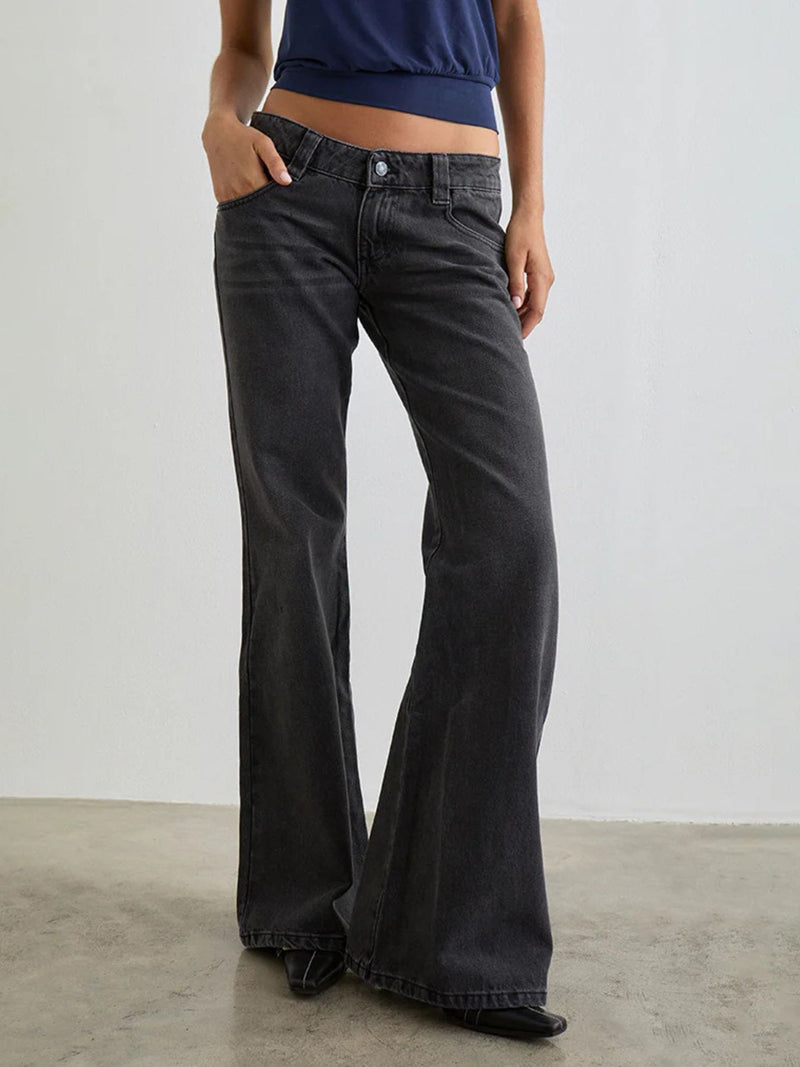 Person wearing black flared jeans and a blue top against a plain background