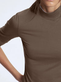 Brown turtleneck shirt worn by a person on a light gray background