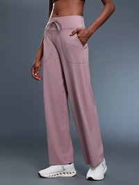 Person wearing mauve pants with a gray background