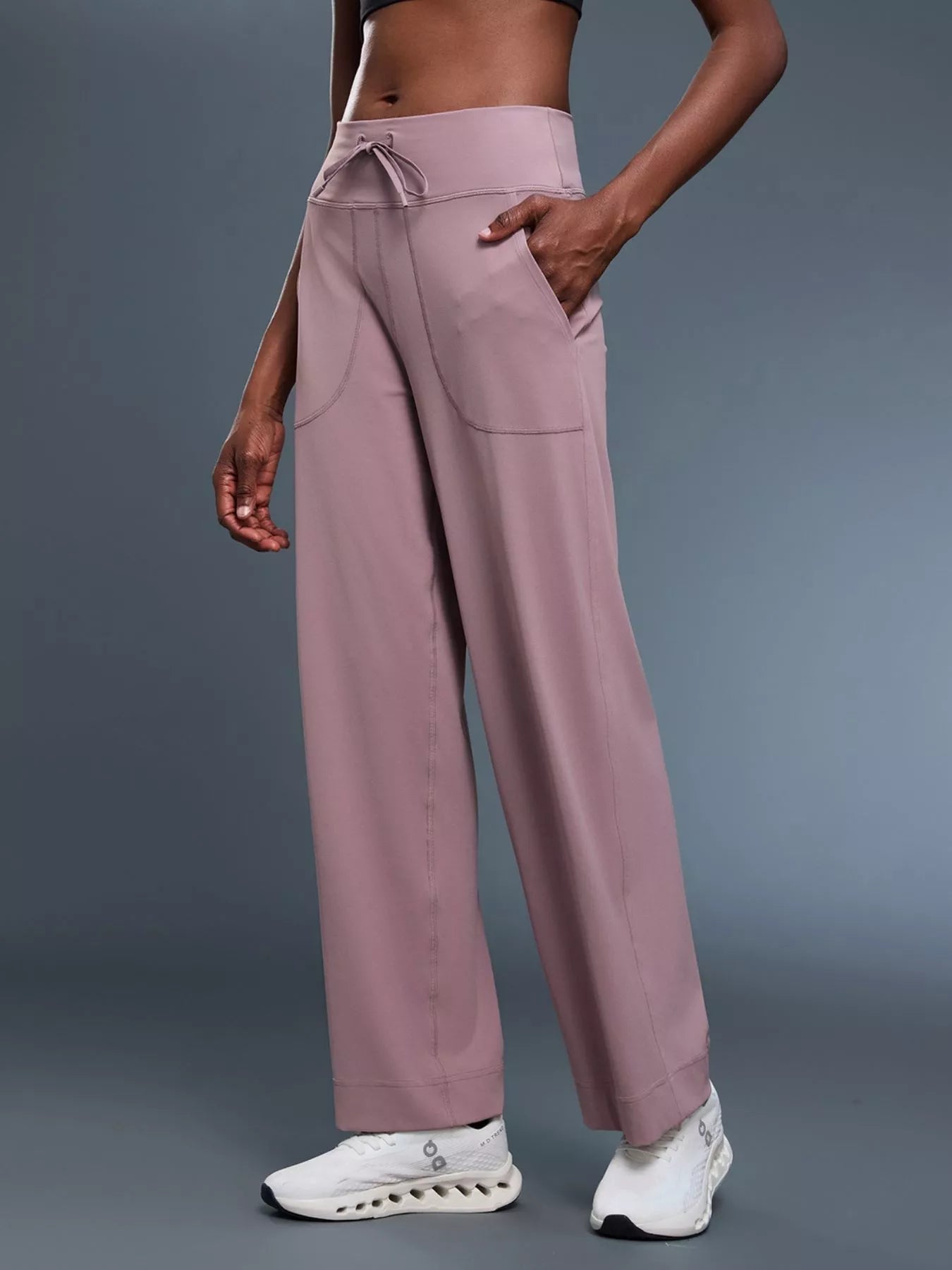 Person wearing mauve pants with a gray background