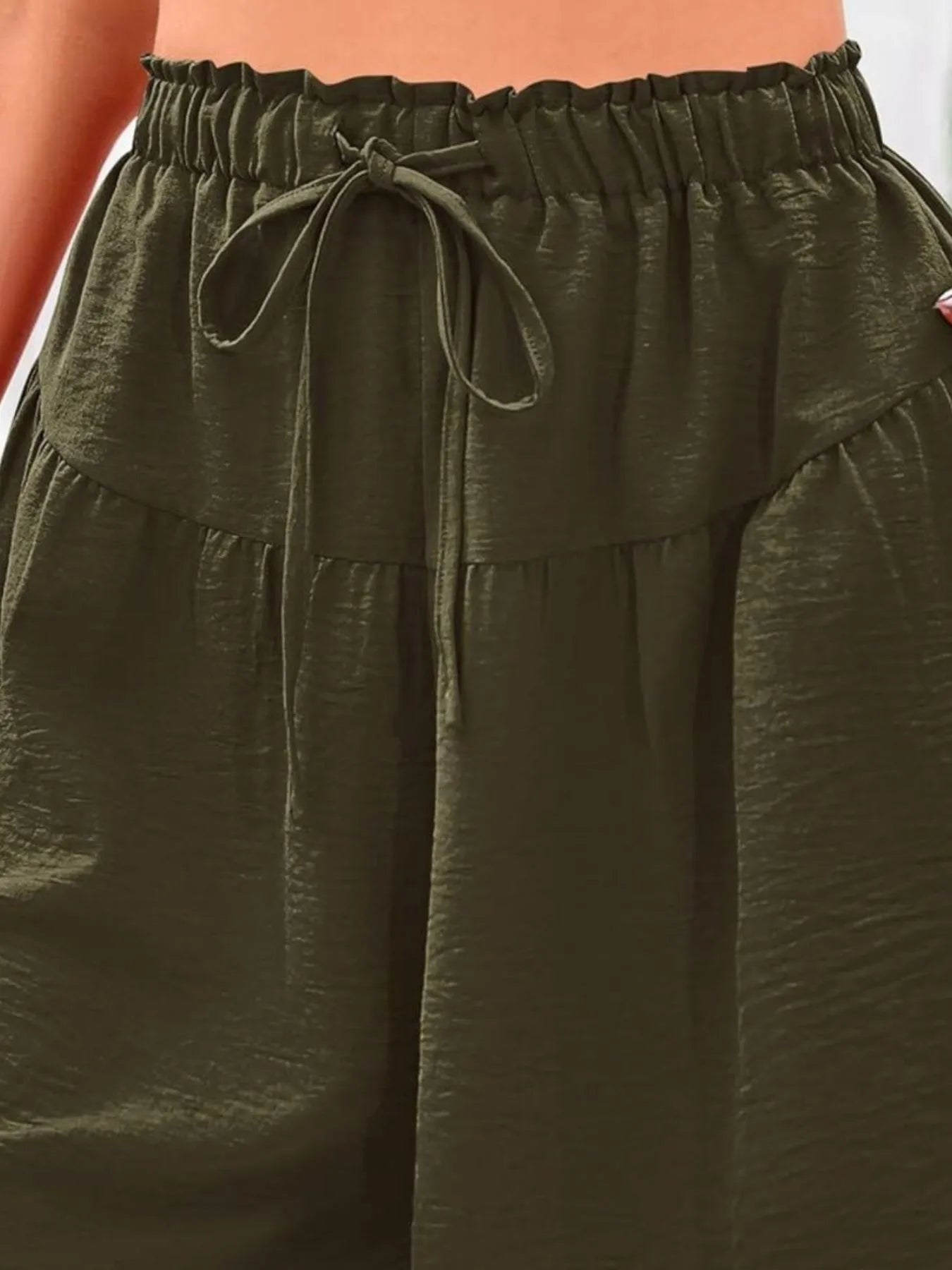 Close-up of olive green pants with a drawstring waistband.