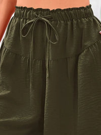 Close-up of olive green pants with a drawstring waistband.
