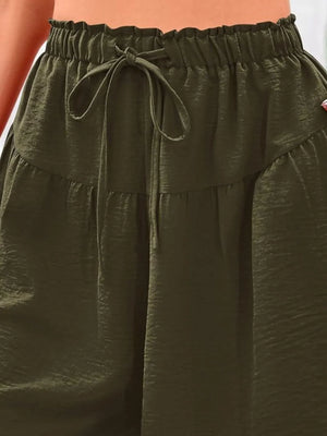 Close-up of olive green pants with a drawstring waistband.