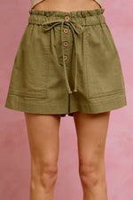 Green shorts with button details on a pink background