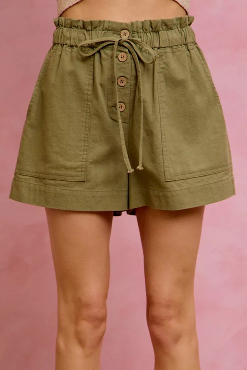 Green shorts with button details on a pink background