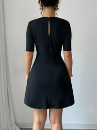Black dress with a back zipper worn by a person against a plain background