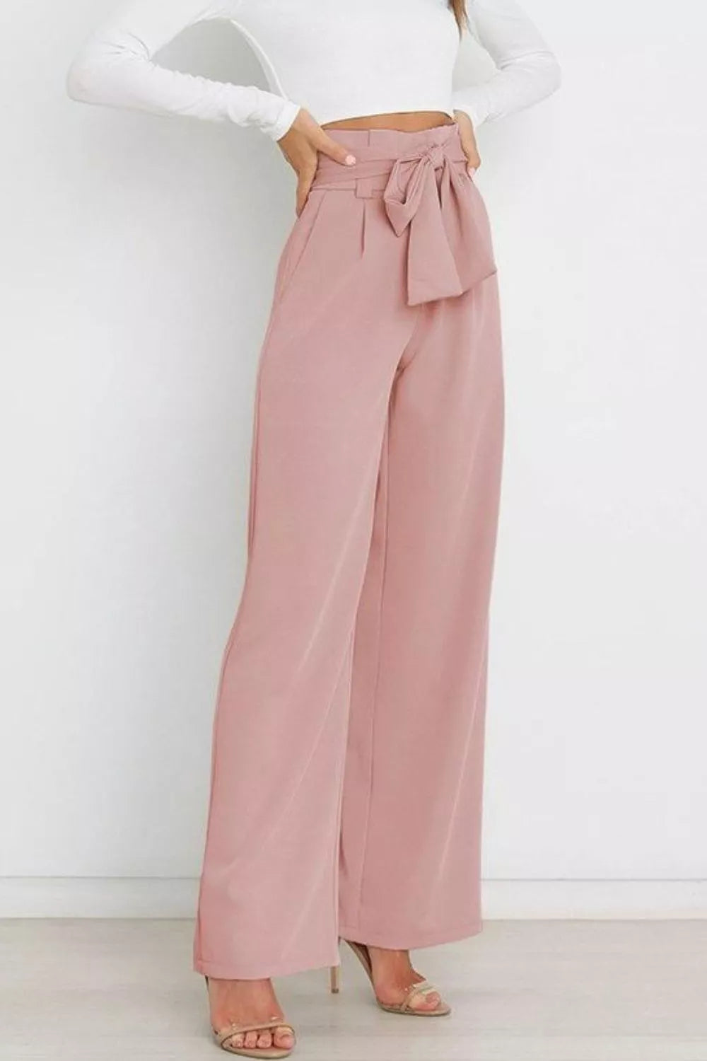 Pink wide-leg pants with a white top on a plain background