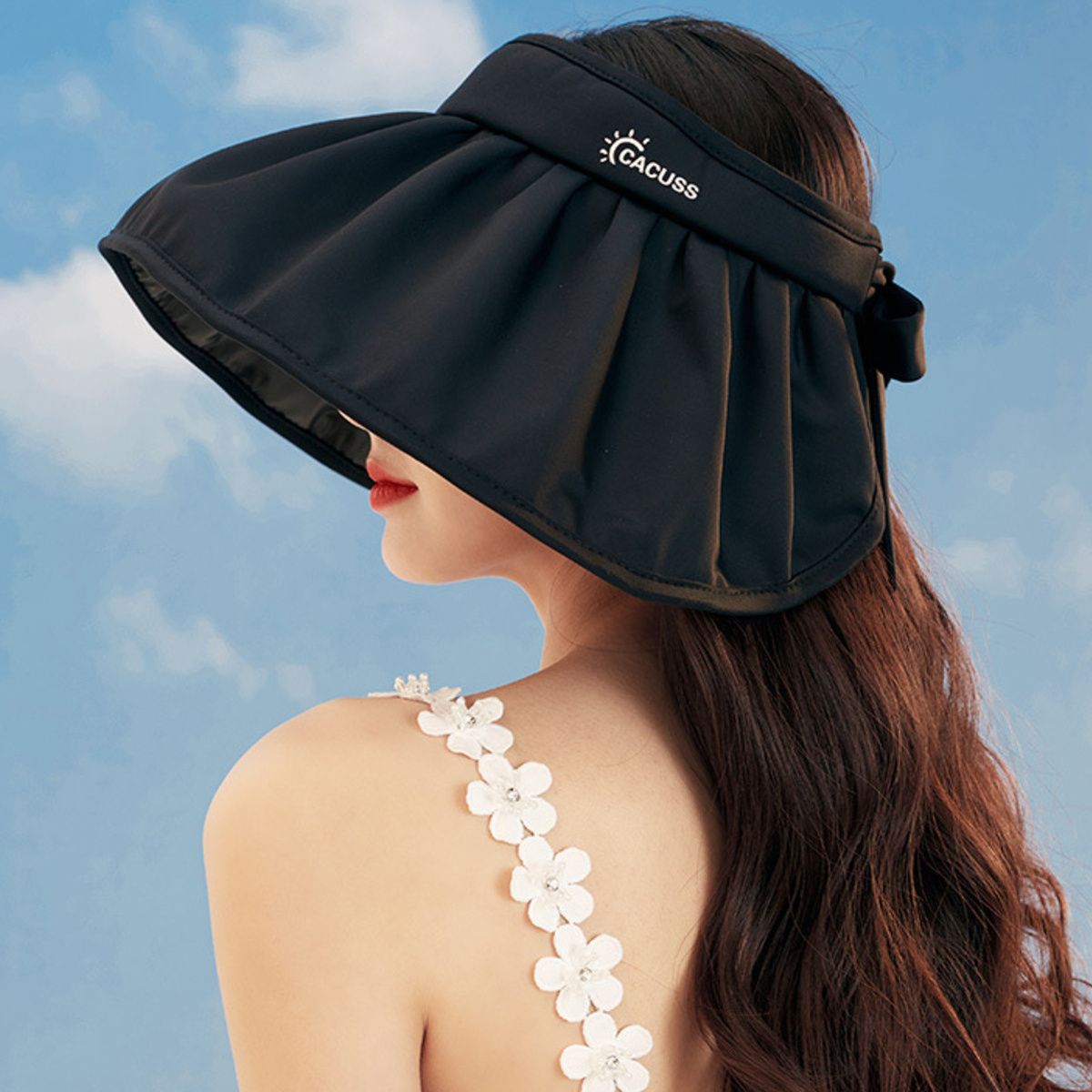 Woman wearing a black visor hat against a blue sky