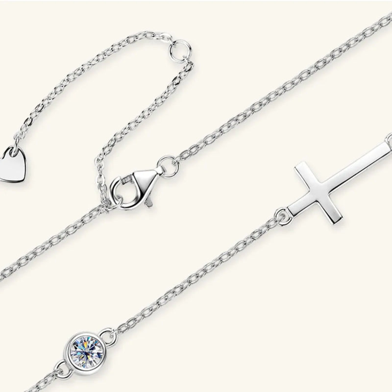 Silver anklets with heart, triangle, and cross charms on a white background